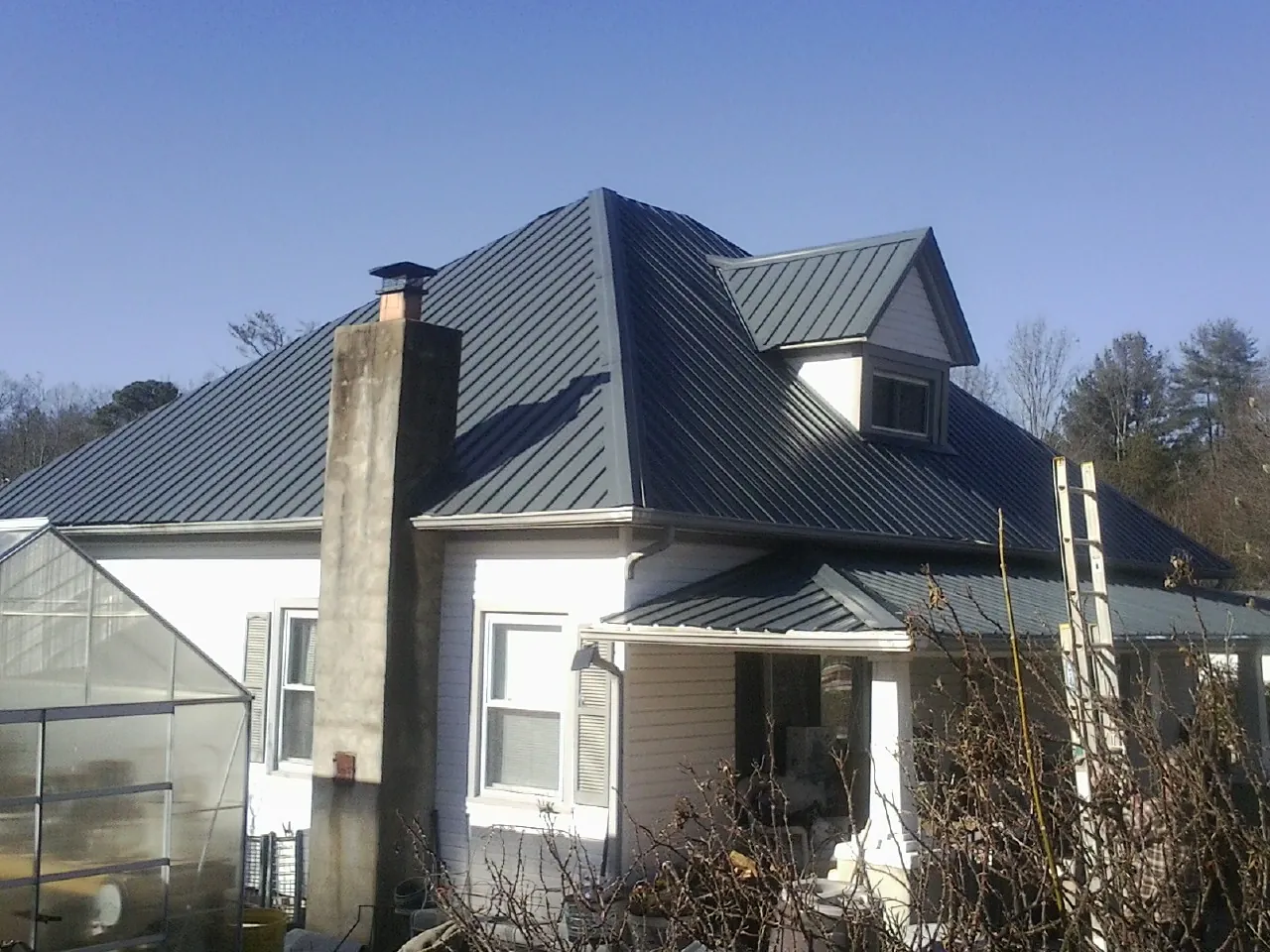 Dark blue standing seam metal roof on a white farmhouse with dormer — Slate & Tile Roof Repair by Roofing Brothers in San Anselmo