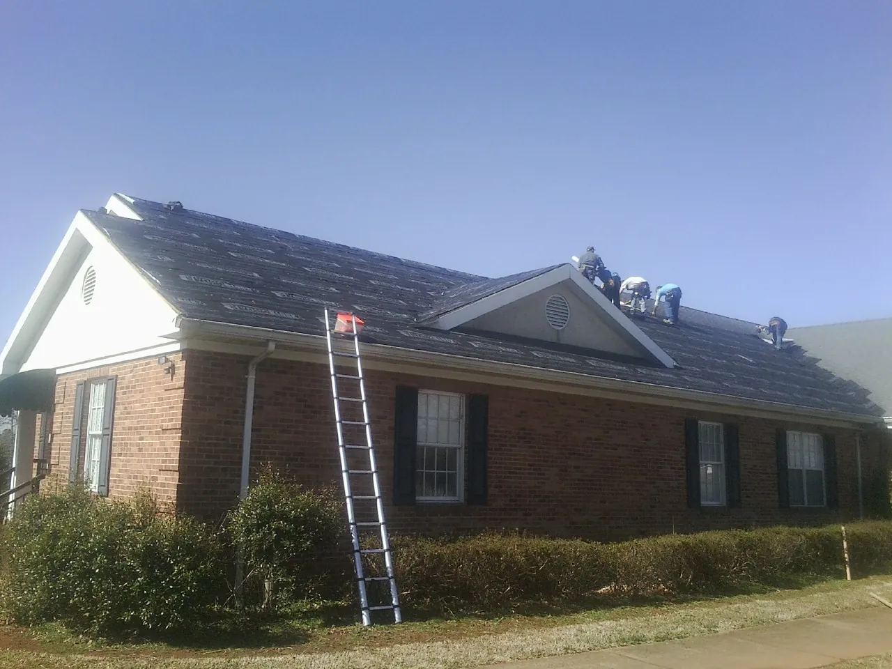 Crew tearing shingles off a brick ranch roof with a ladder set — Metal Roof Repair work by our crew in San Anselmo