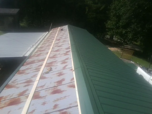 Old rusted panels beside newly installed green metal roofing — Wind Damage Roof Repair by Roofing Brothers in San Anselmo