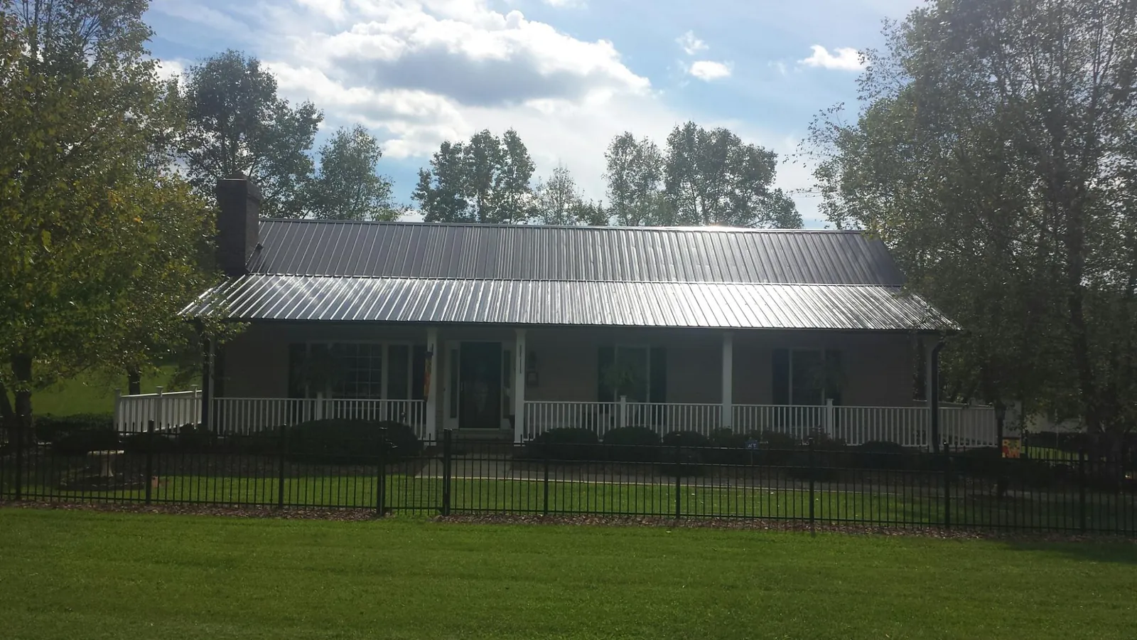 Gray metal roof on a brick ranch with a full width front porch — Gutter Guard Installation work by our crew in San Anselmo