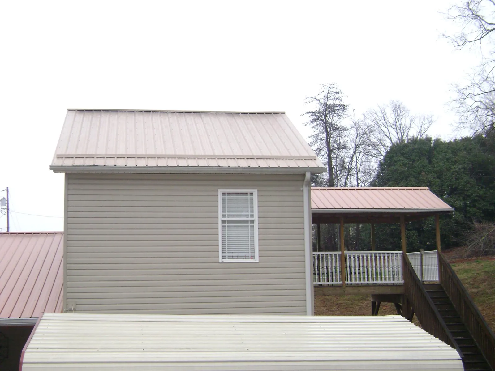 Tan metal roofs on a two story addition and attached porch, from a Roof Replacement job in San Anselmo